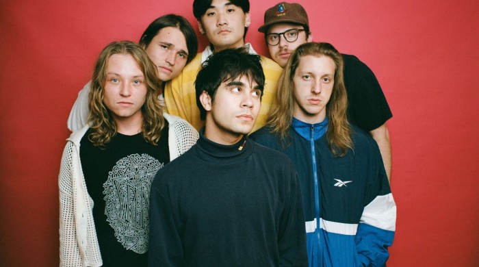 The six members of the band The Sophs in front of a red backdrop